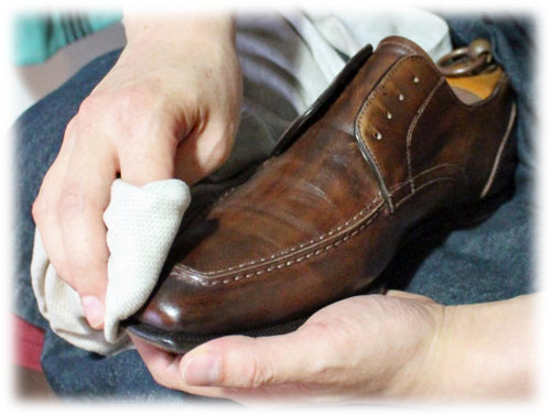 職人が茶色の革靴を靴磨き（手入れ）している写真